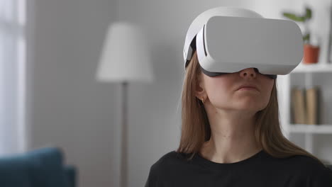 woman-is-viewing-virtual-reality-by-modern-head-mounted-display-in-living-room-medium-portrait-of-female-user-indoors-device-for-video-games-and-education